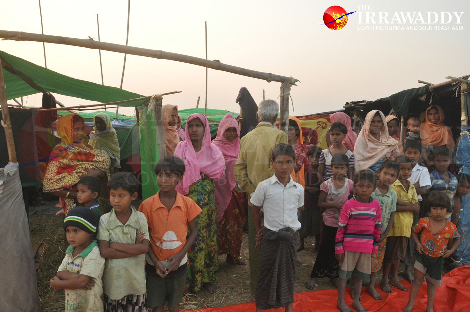 Rohingya women and children—displaced from Dar Gyee Zar village—watch as authorities carry out relief efforts near Abujara village in northern Maungdaw Township. (Photo: Moe Myint / The Irrawaddy)