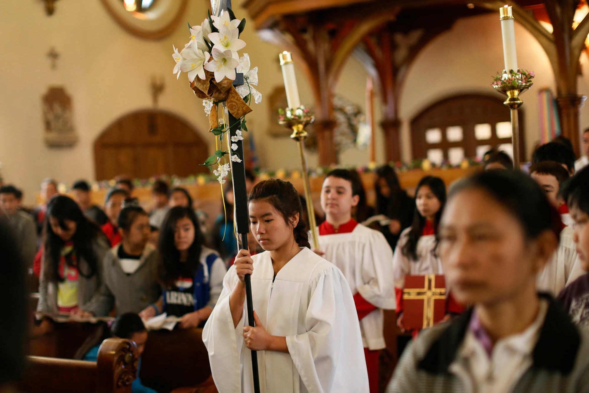 Beh Meh carries the cross to lead the processional at the start of Mass at Our Lady of Hope, April 19, 2015. (Derek Gee/Buffalo News)