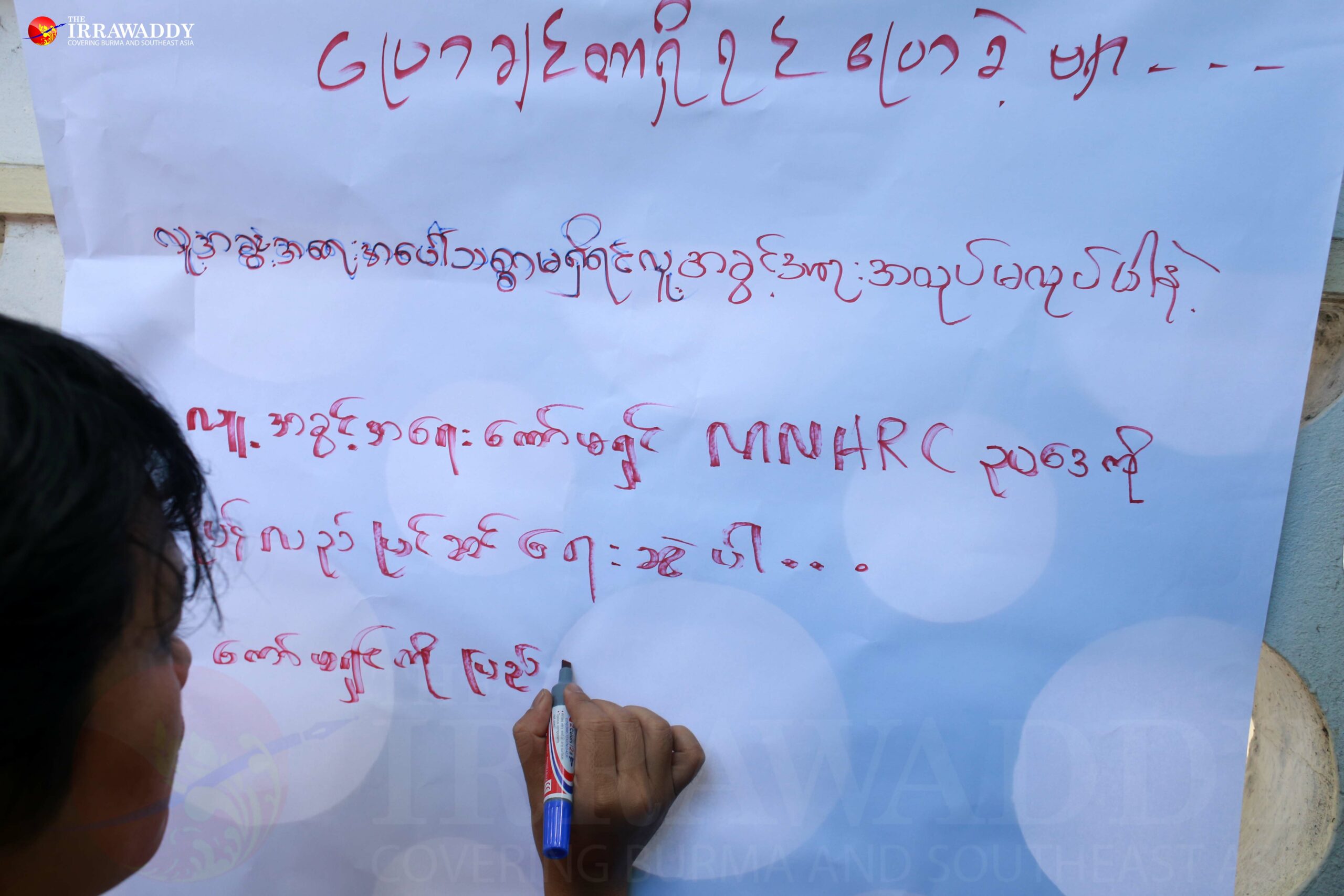 A protester writes a message outside of the MNHRC’s building on Wednesday afternoon, to express dissatisfaction with the commission’s handling of the case of child labor and abuse. 